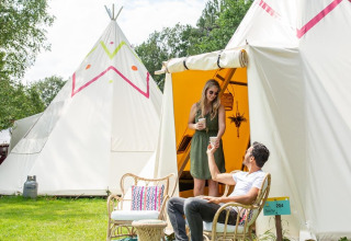 Stel geniet van drankjes bij tipi Jippi Tippi op de Beloofde Land camping in Nederland.
