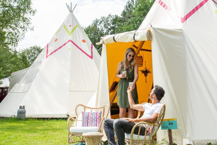 Un couple partage une boisson devant le tipi Jippi Tippi au camping Beloofde Land aux Pays-Bas.