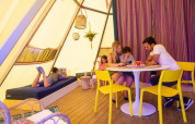 Gezin samen in Jippi Tippi tipi-tent op Beloofde Land, Nederland, kinderen lezen en spelen samen.