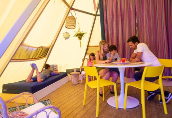 Familia disfruta en la tienda tipi Jippi Tippi del Beloofde Land, Países Bajos, niños juegan y leen.