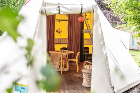 Ingang van de Jippi Tippi tent op Beloofde Land in Nederland met sfeervolle en gezellige inrichting.