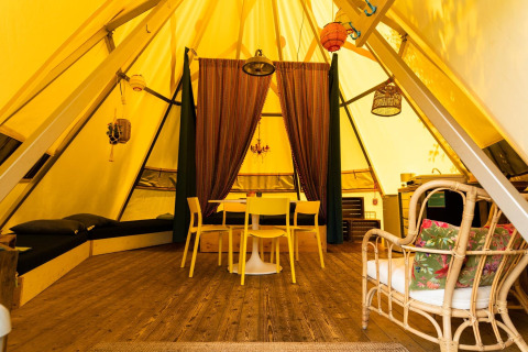 Interieur van de Jippi Tippi tipi tent op Beloofde Land in Nederland, met gezellige houten inrichting.