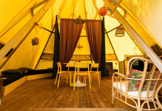 Interieur van de Jippi Tippi tipi tent op Beloofde Land in Nederland, met gezellige houten inrichting.
