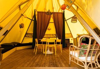 Interior de la tienda tipi Jippi Tippi en Beloofde Land, Países Bajos, con decoración de madera acogedora.
