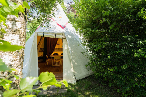Ingang van de Jippi Tippi tent op Beloofde Land in Nederland, omgeven door groene natuur.