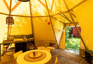 Binnenaanzicht van de Jippi Tippi tent met keuken, eettafel en zithoek op Beloofde Land, Nederland.