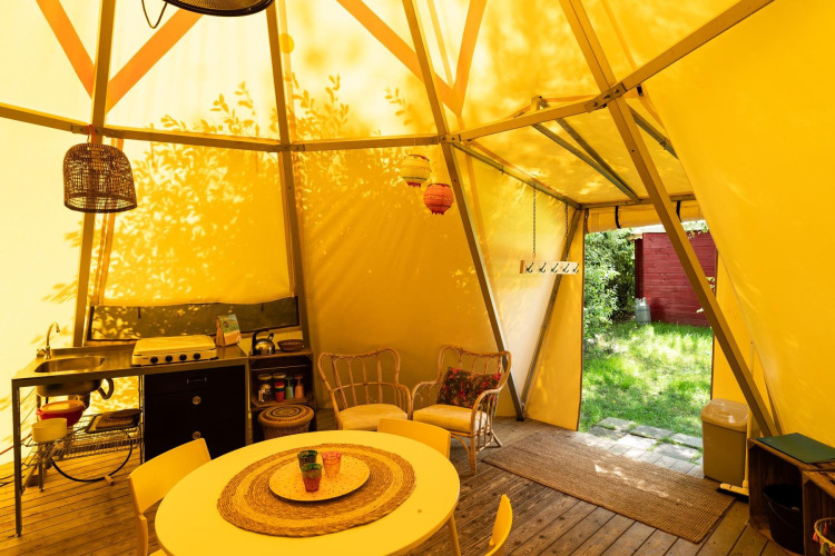 Binnenaanzicht van de Jippi Tippi tent met keuken, eettafel en zithoek op Beloofde Land, Nederland.
