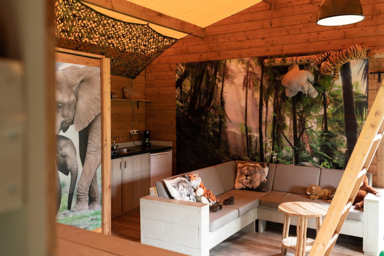 Interior de una tienda safari en Jungle huisje, Beloofde Land, Países Bajos, con cojines y peluches de animales.