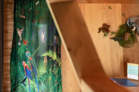 Intérieur de la tente safari Jungle huisje au Beloofde Land, Pays-Bas, avec rideau et déco animaux de jungle.