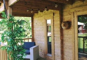 Houten terras met zetel, groen en lichtsnoer bij Jungle huisje safaritent in Beloofde Land, Nederland.