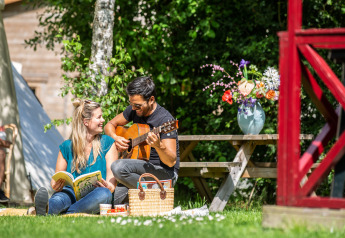 Couple profitant d’un pique-nique avec guitare et livre sur la pelouse de Zweedse Huisjes, Beloofde Land.