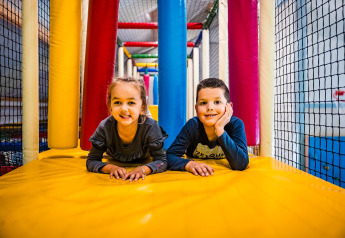 Two children are playing happily on a colorful indoor play area at Zweedse Huisjes in Beloofde Land, Netherlands.
