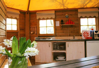 Cuisine chaleureuse en bois avec fleurs et ustensiles dans Zweedse Huisjes au Beloofde Land, Pays-Bas.