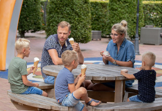 Gezin geniet van ijs en koffie aan een picknicktafel bij Camping de Noetselerberg in Overijssel, Nederland.