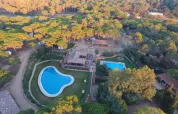 Aerial view of Camping Begur in Catalonia, Spain, featuring swimming pools, buildings, and surrounding forest.