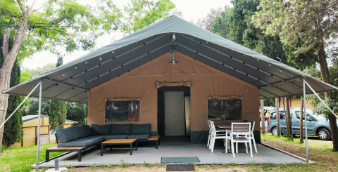 Großes Glampingzelt mit überdachter Terrasse, Sofa und Esstisch im Camping Begur, Katalonien, Spanien.
