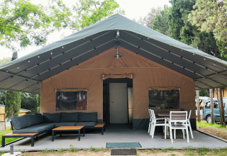Großes Glampingzelt mit überdachter Terrasse, Sofa und Esstisch im Camping Begur, Katalonien, Spanien.