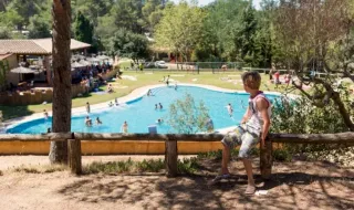 Dreng kigger ud over swimmingpoolen på Camping Begur feriepark i Catalonien, Spanien, på en solskinsdag.