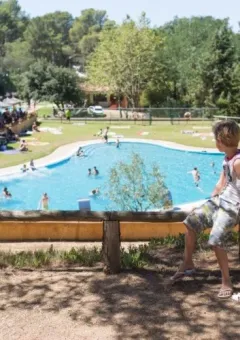 Junge blickt auf den Pool im Camping Begur Ferienpark in Katalonien, Spanien, an einem sonnigen Tag.