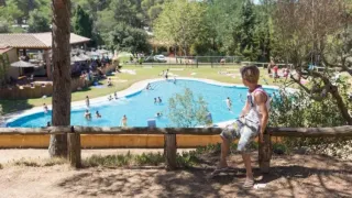 Garçon regardant la piscine du Camping Begur, parc de vacances en Catalogne, Espagne, par une journée ensoleillée.
