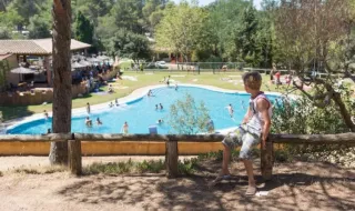 Dreng kigger ud over swimmingpoolen på Camping Begur feriepark i Catalonien, Spanien, på en solskinsdag.
