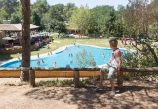 Dreng kigger ud over swimmingpoolen på Camping Begur feriepark i Catalonien, Spanien, på en solskinsdag.