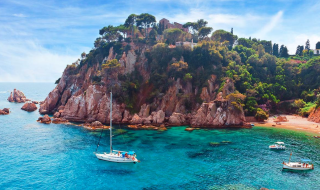Côte rocheuse et bateaux près de Palafrugell, Catalogne, Espagne sous un ciel bleu et eaux cristallines.