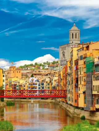 Rives colorées, bâtiments et pont rouge près de Palafrugell, en Catalogne, Espagne, sous un ciel bleu éclatant.