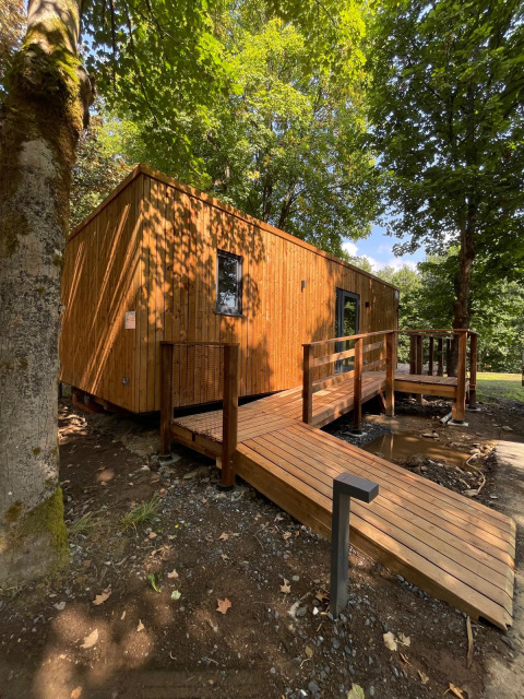 Ecolodge - Zorgtoegankelijk, moderna cabaña de madera en el bosque con rampa accesible hacia la entrada.