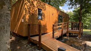 Ecolodge - Zorgtoegankelijk, a modern wooden cabin in the woods with an accessible ramp to the entrance.