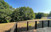 View from wooden deck at Ecolodge - Zorgtoegankelijk, Hameau de l'Ourthe, Belgium with sunny sky.