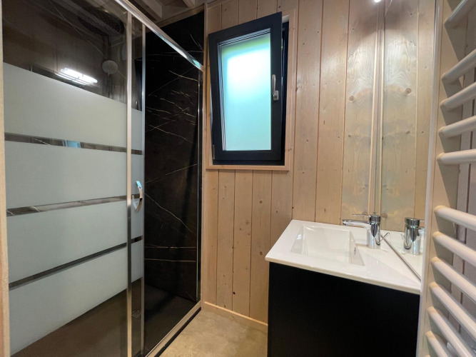 Moderne badeværelse med bruseniche, dobbelt håndvask og træpaneler på Ecolodge ved Hameau de l'Ourthe.