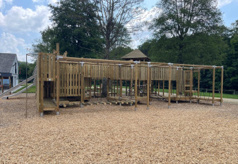 Foto de un parque infantil de madera con redes para escalar y tobogán en un alojamiento glamping.