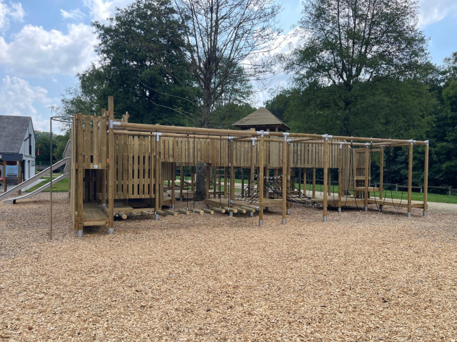 Foto de un parque infantil de madera con redes para escalar y tobogán en un alojamiento glamping.
