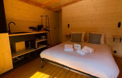 Interieur van een boomhut in Hameau de l'Ourthe, België, met houten afwerking, een bed en invallend zonlicht.