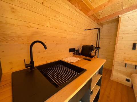 Moderne spoelbak en houten interieur in Tree House bij Hameau de l'Ourthe, België, knusse sfeer.