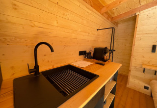 Moderne spoelbak en houten interieur in Tree House bij Hameau de l'Ourthe, België, knusse sfeer.