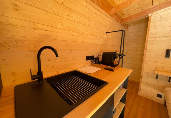 Fregadero moderno y paredes de madera en Tree House del Hameau de l'Ourthe, Bélgica, ambiente acogedor.
