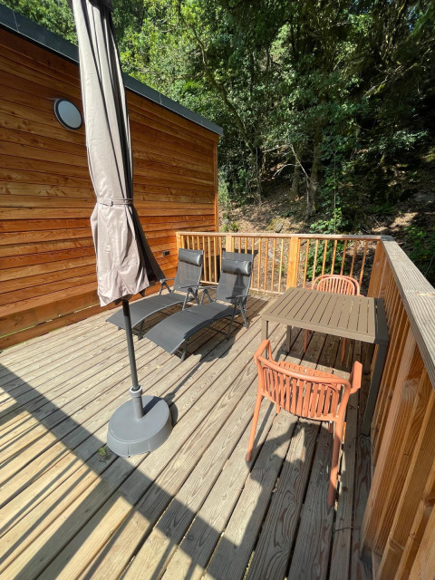 Houten terras met stoelen en tafel aan Tree House in Hameau de l'Ourthe, België, tussen het groen.
