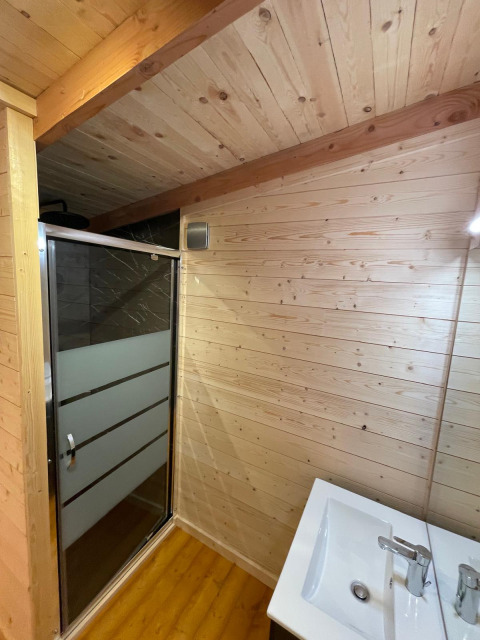 Badkamer in een boomhut met houten muren, moderne douche en lavabo, Hameau de l'Ourthe, België.