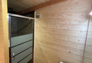 Badkamer in een boomhut met houten muren, moderne douche en lavabo, Hameau de l'Ourthe, België.