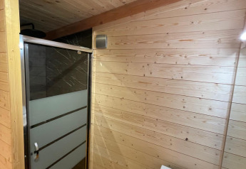 Baño en una casa del árbol con paneles de madera, ducha moderna y lavabo, Hameau de l'Ourthe, Bélgica.