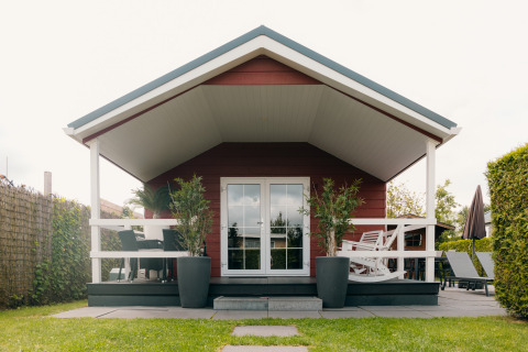 Forreste udsigt af Veluwe Lounge + Sauna lodge med terrasse, planter og havemøbler i De Boshoek, Holland.