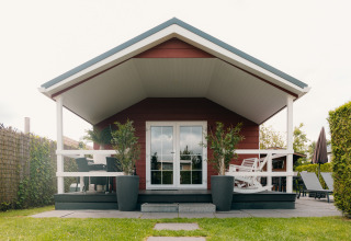Forreste udsigt af Veluwe Lounge + Sauna lodge med terrasse, planter og havemøbler i De Boshoek, Holland.