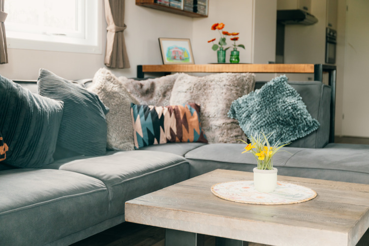 Zona de descanso acogedora en la Veluwe lounge con sofá esquinero y flores en De Boshoek, Países Bajos.