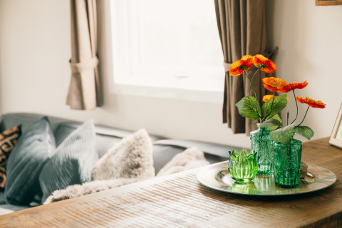 Sala luminosa en Veluwe lounge + sauna, Holiday park De Boshoek, con jarrones verdes y flores naranjas.