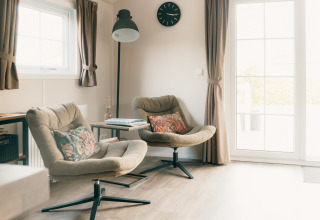 Salotto luminoso al Veluwe lounge + sauna, Holiday park De Boshoek, Paesi Bassi, con due poltrone accoglienti.