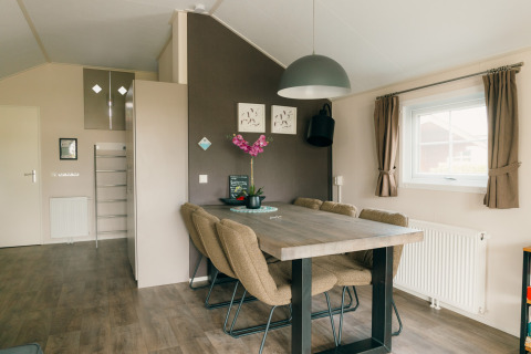 Comedor con mesa moderna, seis sillas y ventana grande en Veluwe lounge + sauna, De Boshoek, Países Bajos.
