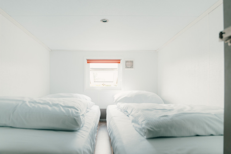 Habitación luminosa con dos camas individuales y ropa blanca en Veluwe lounge + sauna, De Boshoek, Países Bajos.