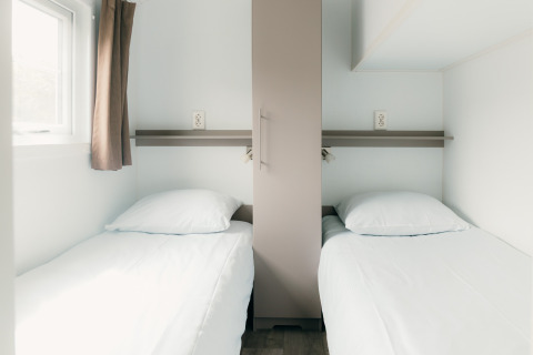 Due letti singoli in una camera minimalista al Veluwe lounge + sauna, Holiday park De Boshoek, Paesi Bassi.